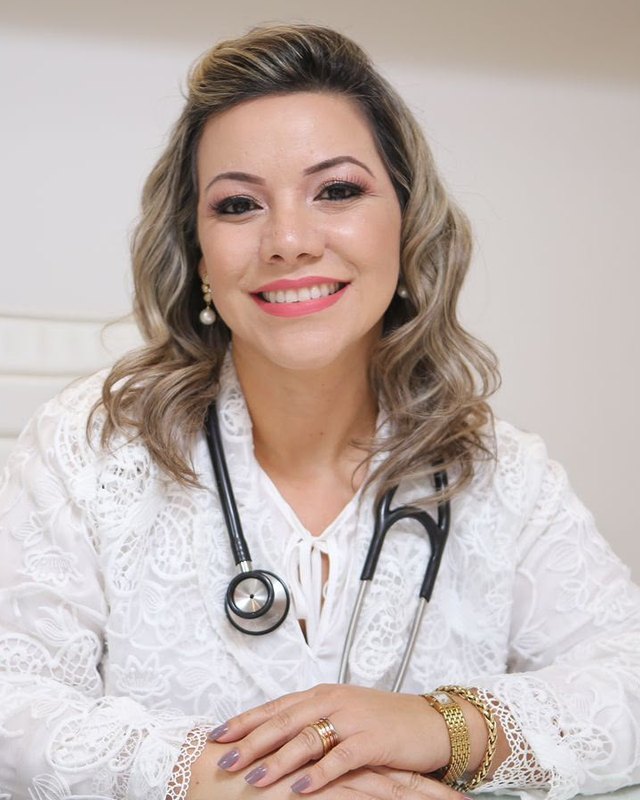 Dra. Priscylla G. Ribeiro, de jaleco branco e estetoscópio, sorrindo